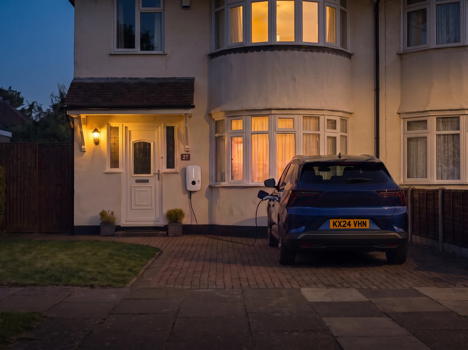 Evening. Martin's car charging on his drive, the windows lit.